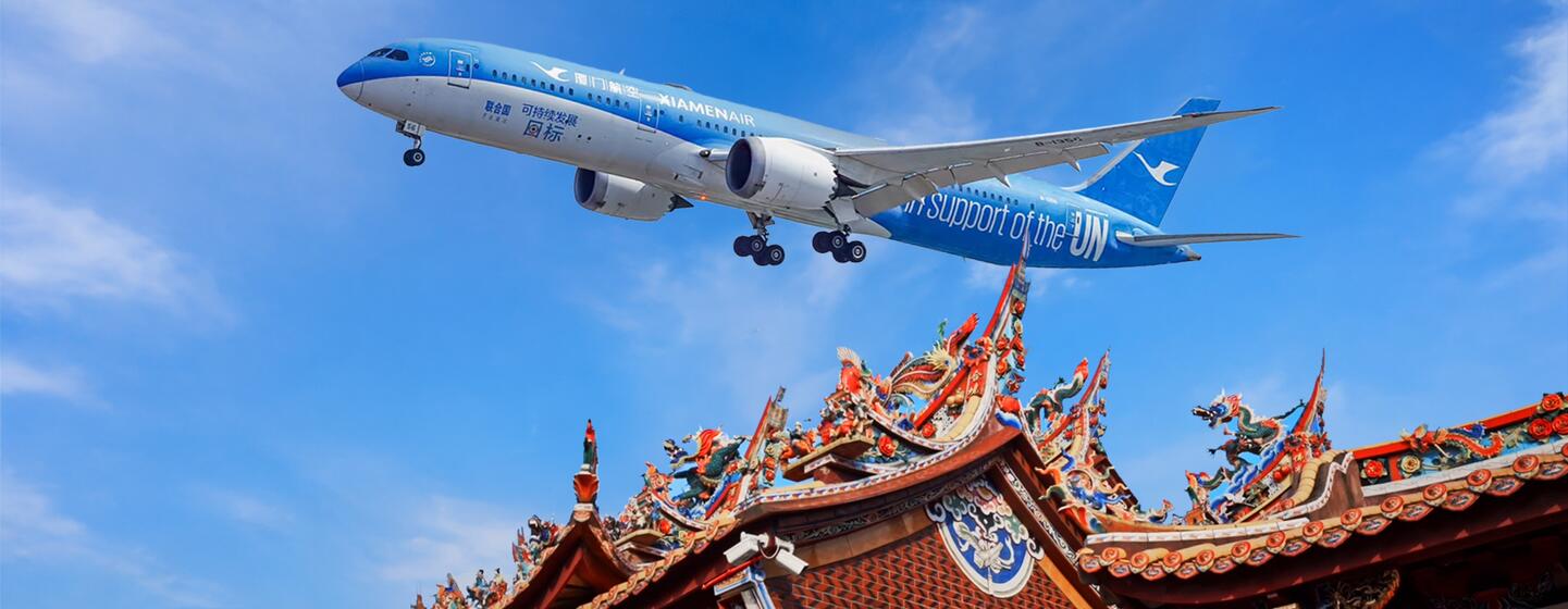 厦门航空的一架飞机飞过一座装饰华丽的中国寺庙屋顶，背景是蔚蓝的天空。