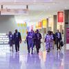 A group of attendees walks through a brightly lit conference hall at the Second World Summit on Social Development in Doha, 2025.