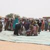 Women and aid workers at a food distribution site in Adre, Chad. Refugees receive bags of food aid from the World Food Programme (WFP) in the desert.