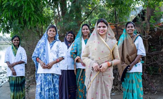 सरपंच पूजा साहू और जल वाहिनी एक ग्रामीण भारतीय गांव में एक साथ खड़ी हैं।