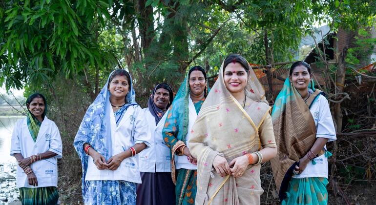 सरपंच पूजा साहू और जल वाहिनी एक ग्रामीण भारतीय गांव में एक साथ खड़ी हैं।