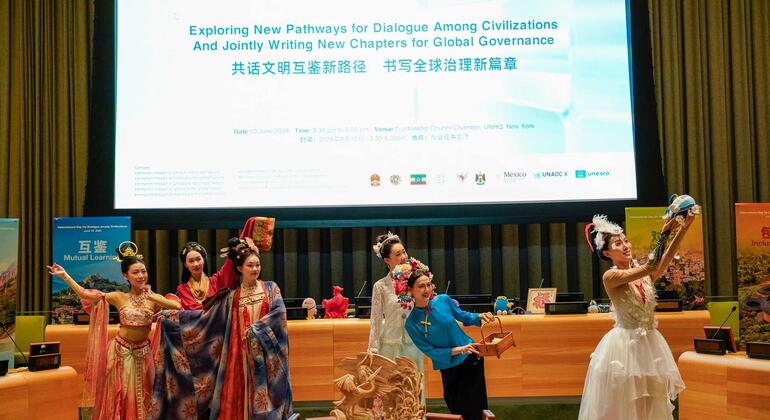 在纽约联合国总部，身着中国传统服饰的表演者在大屏幕前的舞台上翩翩起舞。