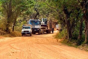 Un convoi de véhicules, dont un camion de ONU , circule sur une piste de terre à travers une forêt de la République démocratique du Congo.