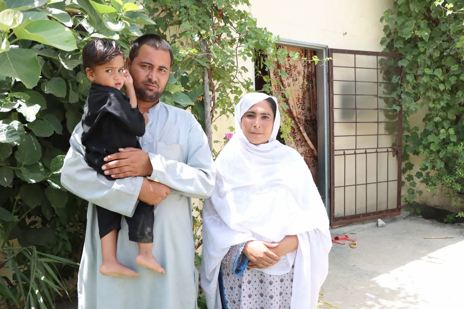 پاکستان کے ایک صحن میں ایک نوجوان لڑکے کو پکڑے ایک شخص ایک عورت کے پاس کھڑا ہے۔