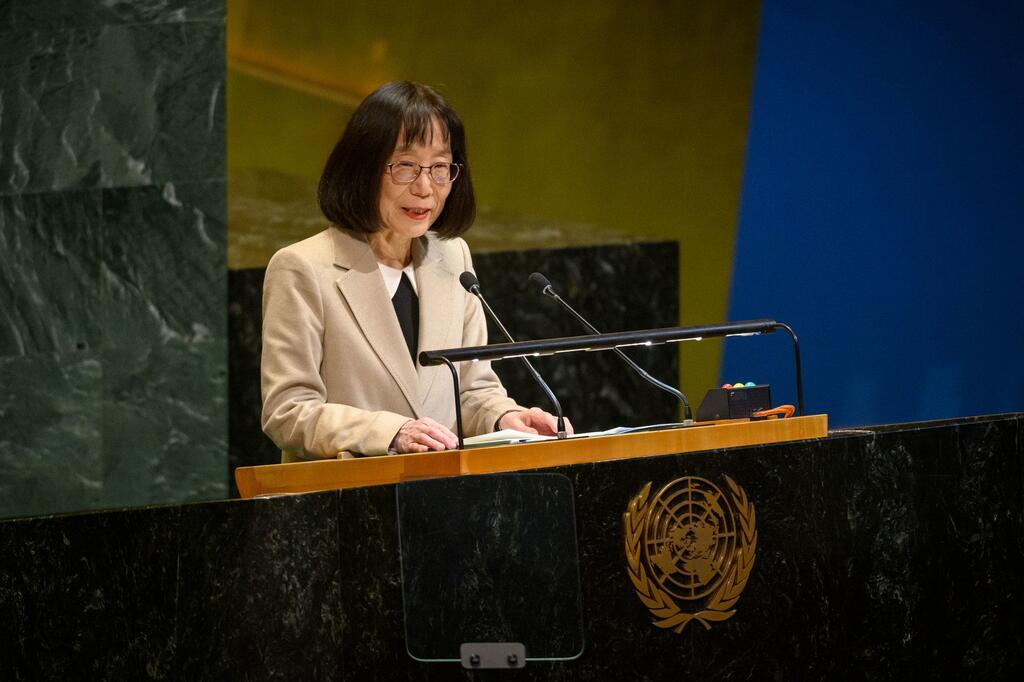 Japanese woman Tomoko Akane speaks at a podium bearing the United Nations emblem.