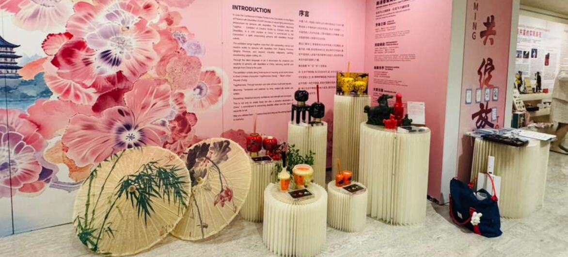 展览展示品包括一幅大型粉色花卉壁画、中国传统阳伞以及摆放在基座上的文化文物。