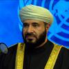 رجل ملتحٍ ويرتدي عمامة بيضاء يتحدث في ميكروفون، ويظهر شعار United Nations في الخلفية.