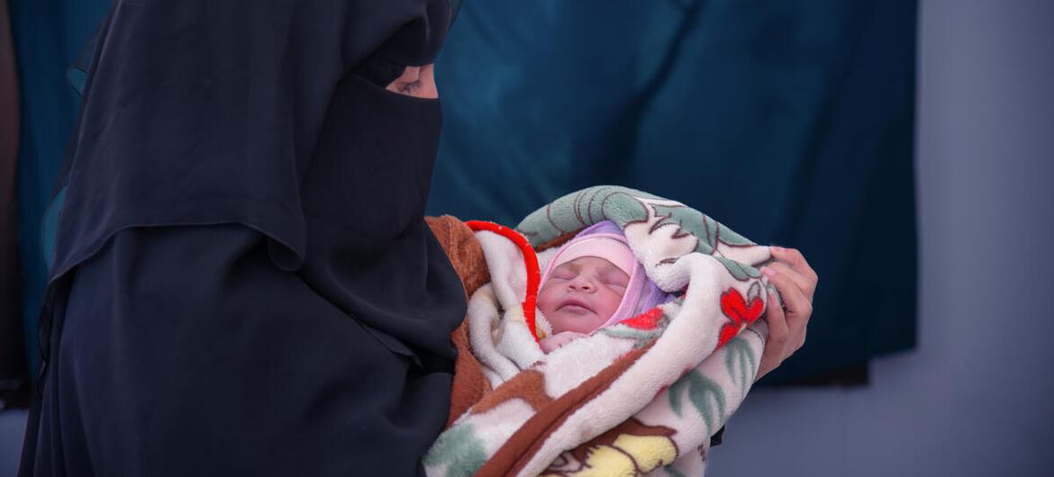 یمن میں نقاب پہنے ایک خاتون نے ایک نوزائیدہ بچے کو کمبل میں لپیٹ رکھا ہے۔