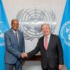UN Secretary-General António Guterres and Youssouf shake hands in front of the UN emblem and two UN flags.
