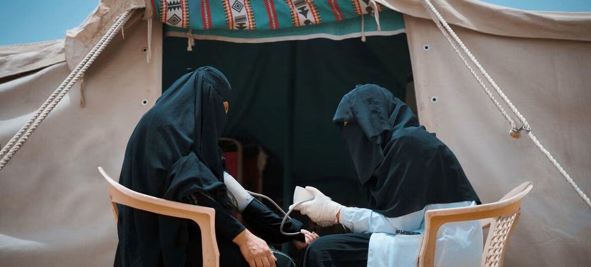 یمن میں UNFPA ایک طبی کارکن ایک عارضی خیمے میں ایک خاتون مریضہ کا بلڈ پریشر چیک کر رہا ہے۔