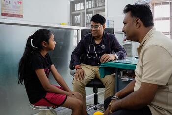 A doctor consults with a young girl and her father in a clinic in India, as part of a UNICEF diabetes treatment program.