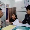 एक डॉक्टर क्लिनिक में एक छोटी लड़की और उसके पिता की जांच कर रहा है और डेस्क पर रखे मेडिकल रिकॉर्ड की समीक्षा कर रहा है।