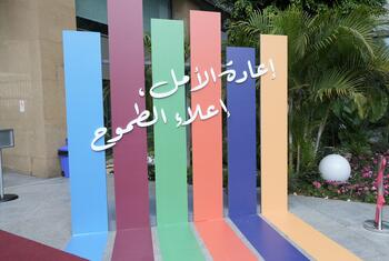 أعمدة عمودية ملونة تحمل شعار ESCWA ونصاً عربياً عند مدخل مبنى حديث.