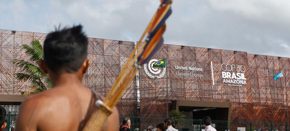 Un arquero indígena con un carcaj de flechas se encuentra frente al edificio de la COP30 en Brasil.