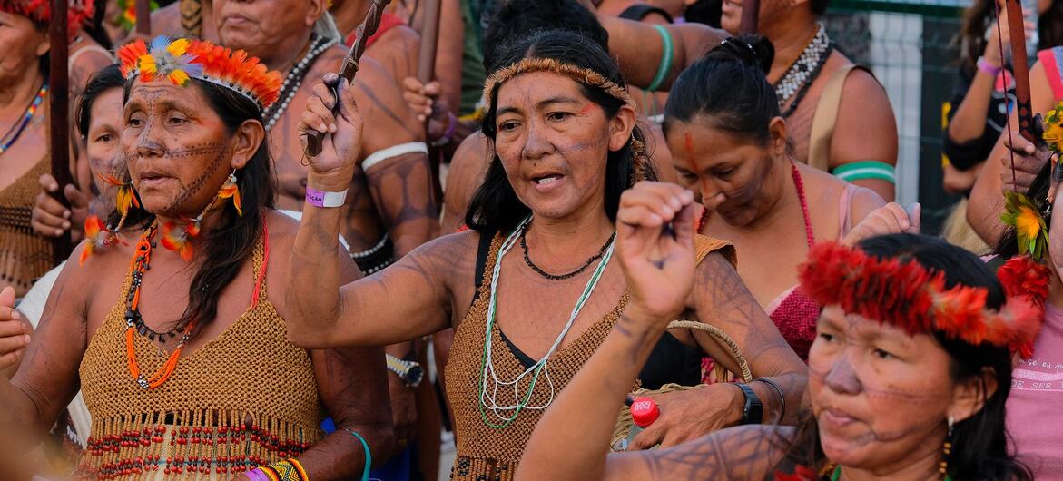 Mujeres indígenas con vestimenta tradicional y tocados de plumas participan en una manifestación en la COP30 en Belém.