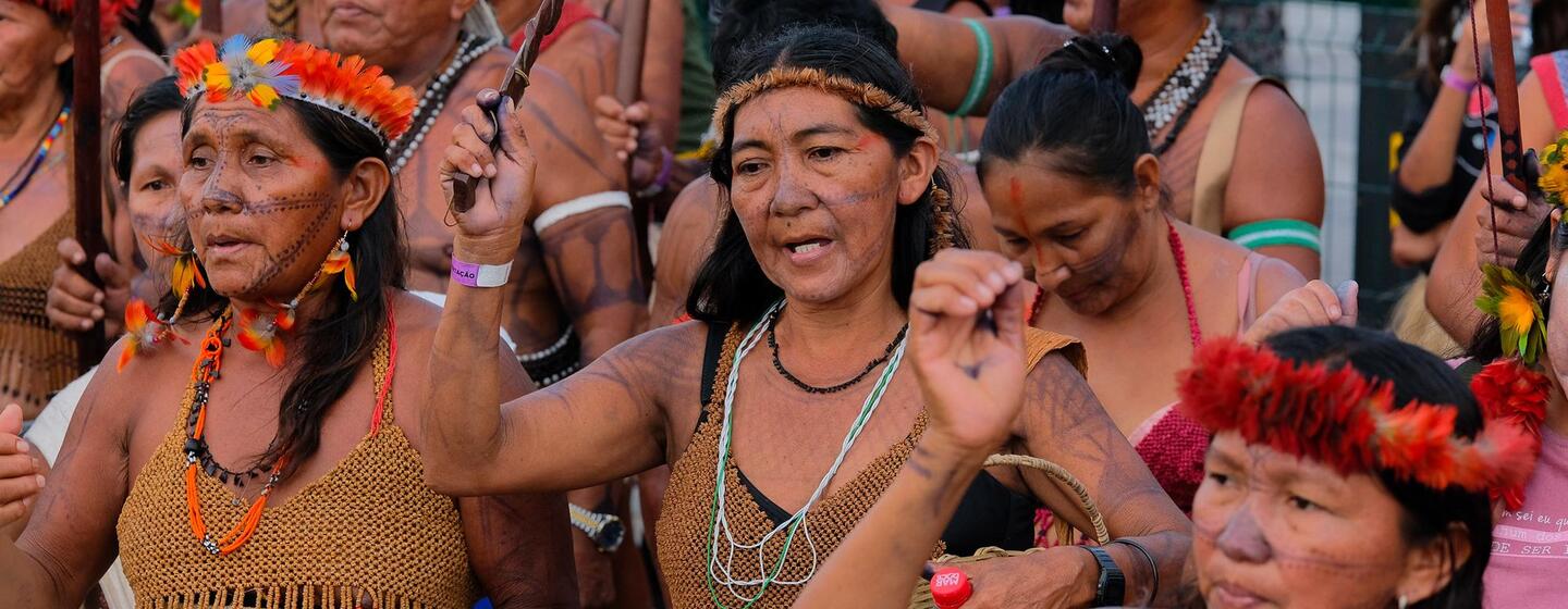 Des femmes indigènes en tenue traditionnelle et coiffes de plumes participent à une manifestation lors de la COP30 à Belém.