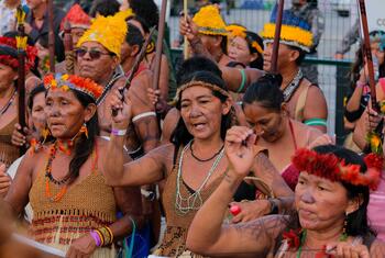 Mujeres indígenas con vestimenta tradicional y tocados de plumas participan en una manifestación en la COP30 en Belém.