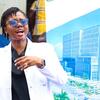 Mwanamke aliyevaa koti jeupe la maabara na miwani ya jua akizungumza na kuonyesha ishara katika hafla moja nchini Tanzania.