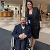 Rafael Bonfim e Maria Junqueira Airoldi Cosp posam juntos no saguão de um prédio.