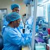 Duas técnicas de laboratório, usando equipamentos de proteção individual, trabalham em uma cabine de segurança biológica em um laboratório em Bunia, República Democrática do Congo.