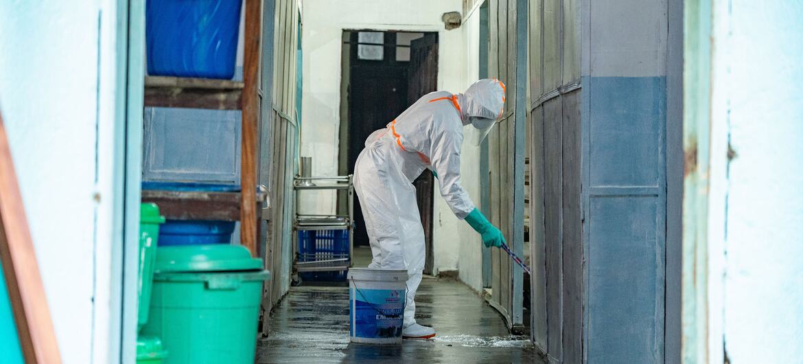 Mfanyakazi wa afya akiwa amevaa vifaa kamili vya kujikinga akiua vijidudu kwenye korido ya hospitali katika Kituo cha Matibabu cha Kiinjili huko Bunia, DR Congo.