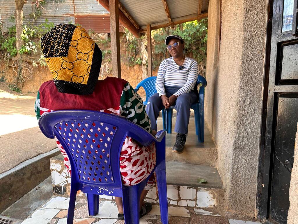 Mwanasaikolojia wa WHO Julienne Anoko ameketi kwenye varanda huko Bunia, DRC, akizungumza na mwanamke aliyepoteza wanafamilia wake kutokana na Ebola.