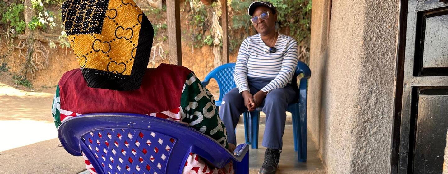 L’anthropologue de l’OMS Julienne Anoko est assise sur une véranda à Bunia, en RDC, et discute avec une femme qui a perdu des membres de sa famille à cause d’Ebola.