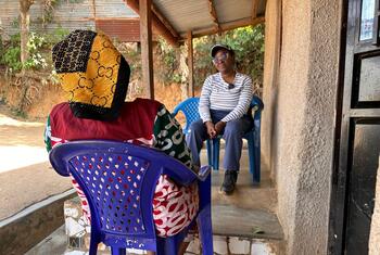 L’anthropologue de l’OMS Julienne Anoko est assise sur une véranda à Bunia, en RDC, et discute avec une femme qui a perdu des membres de sa famille à cause d’Ebola.