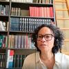 Valika Smeulders, portant un casque et des lunettes, prend la parole lors d'une discussion en direct devant une bibliothèque.