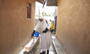 Mwanachama wa timu ya kusafisha uchafu akiwa amevaa suti ya hatari akinyunyizia dawa jengo huko Bunia, Jamhuri ya Kidemokrasia ya Kongo.