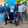 Kundi la vijana wa kiume na wa kike wa Kitanzania wakipiga picha nje mbele ya bango la UNICEF na TACAIDS, kama sehemu ya mpango wa afya ya vijana.