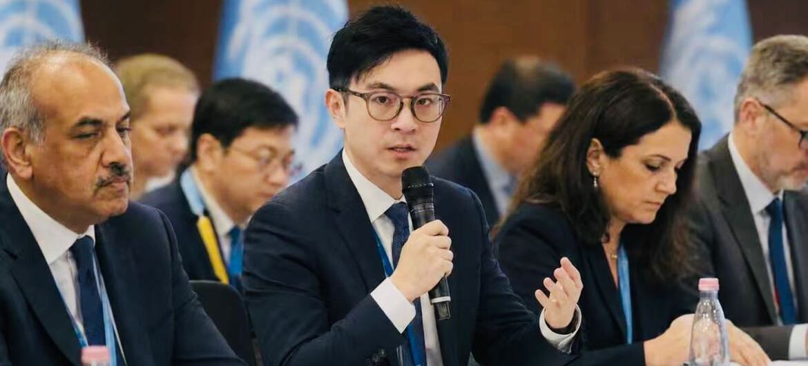 张佩佩在正式的会议桌旁对着麦克风讲话，背景是联合国旗帜。