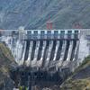 Una gran presa de hormigón atraviesa un valle de montaña, y el agua se libera a través de múltiples aliviaderos.