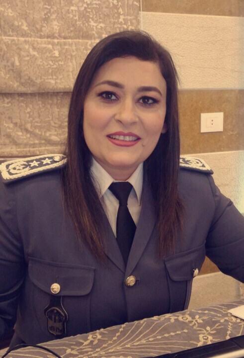 شرطية ترتدي زيًا رسميًا مزينًا برتب عسكرية، تبتسم للكاميرا.
