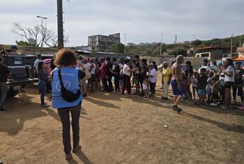 Un voluntario de la ONU distribuye ayuda a un grupo de personas en La Guaira, Venezuela, tras un terremoto.