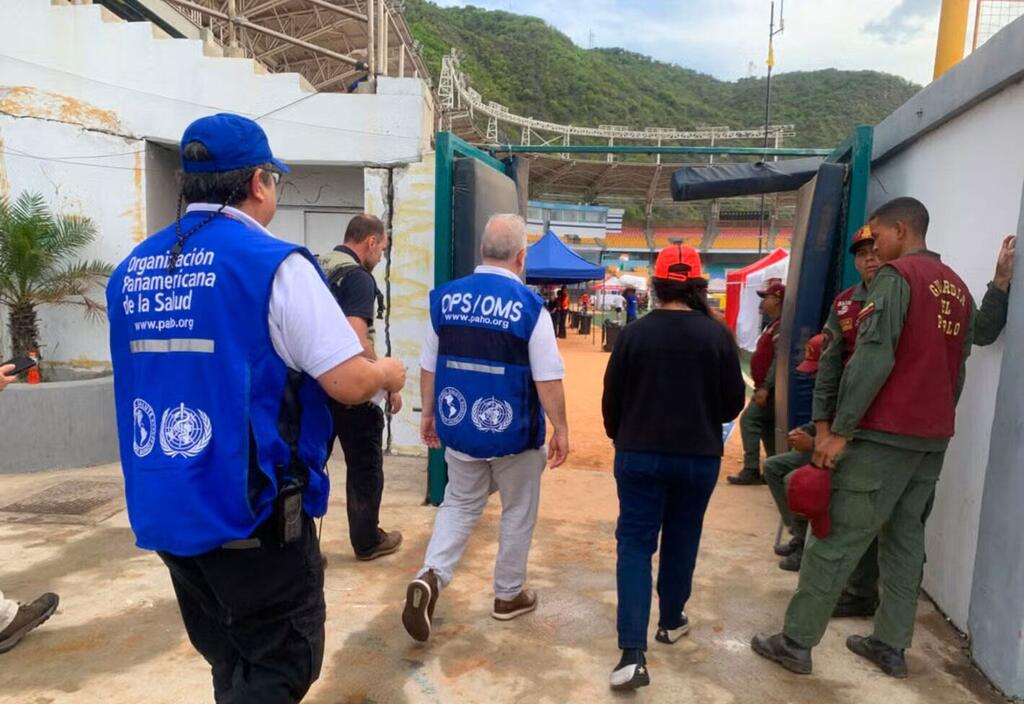 Health workers from PAHO and WHO walk through the entrance of a damaged stadium in Caracas, Venezuela, as part of an emergency response to earthquakes.