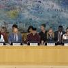 مسؤولون في اجتماع UN Human Rights Council في جنيف، مع لوحات تحمل أسماء الرئيس والأمين العام والمفوض السامي لحقوق الإنسان على الطاولة.
