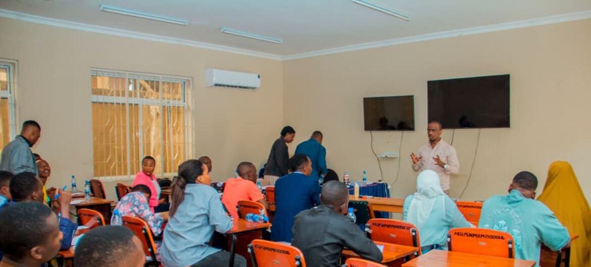 Kipindi cha mafunzo ya vijana UNDP nchini Tanzania, huku washiriki wakiwa wameketi kwenye madawati darasani wakimsikiliza mzungumzaji aliye mbele.