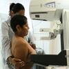 Uma profissional médica auxilia uma mulher mexicana na realização de uma mamografia utilizando um aparelho LORAD em um ambiente clínico.