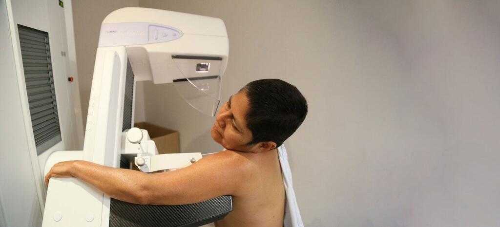 Mwanamke akifanyiwa uchunguzi wa mammogram katika mazingira ya kliniki.