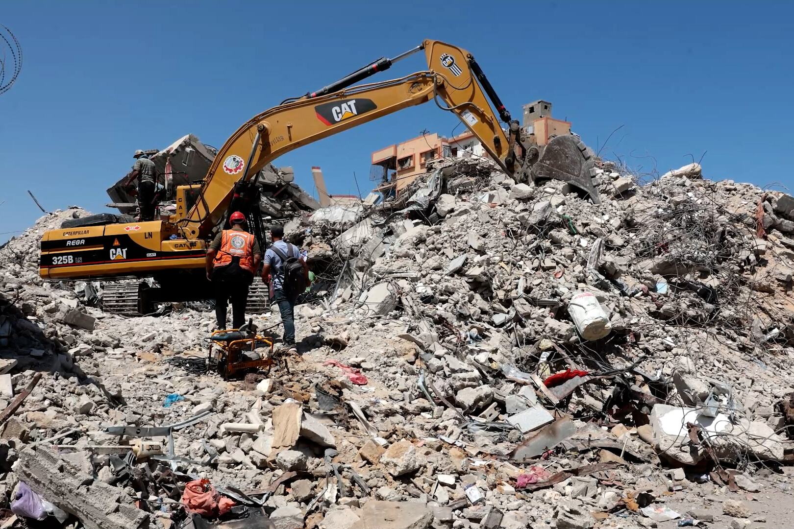 عمال الدفاع المدني الفلسطيني يبحثون عن ضحايا تحت الأنقاض باستخدام حفارة من طراز CAT 325B في غزة.