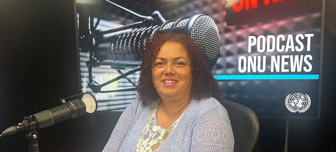 Tania Romualdo sorri para uma foto enquanto está sentada em um estúdio de gravação de podcast.