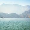 A traditional dhow boat on the water with mountains in the background near Musandam, Oman.