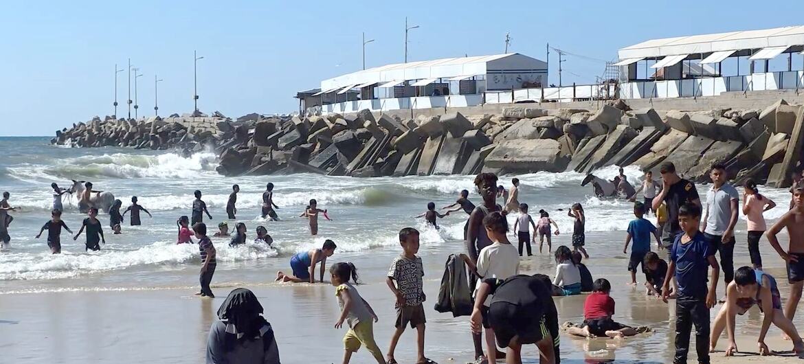 Children play and swim in the waves at Gaza City's beach to escape the summer heat.
