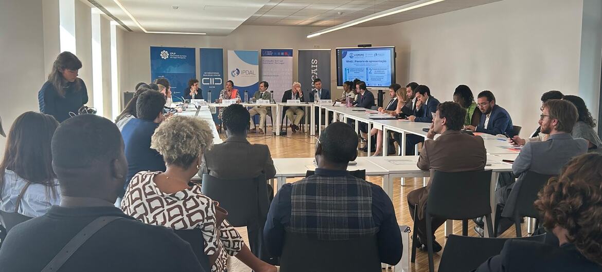 Um grupo de jovens e painelistas participa de uma reunião no Diálogo Pan-Africano da Juventude do CPLP, em uma sala de conferências moderna.