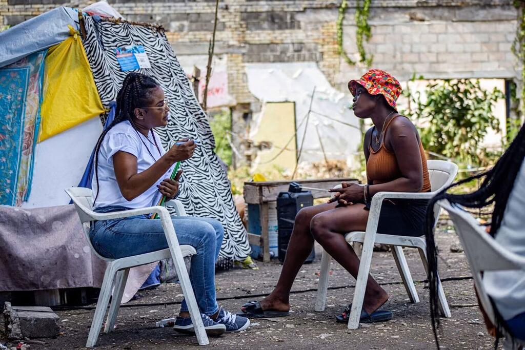Une employée de l'OPS/OMS apporte un soutien psychologique à une femme déplacée dans un site de personnes déplacées internes en Haïti.