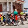 A group of people walk along a street in Port-au-Prince, Haiti, carrying suitcases and bags on their heads.