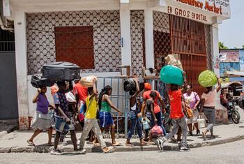 Un groupe de personnes marche dans une rue de Port-au-Prince, en Haïti, portant des valises et des sacs sur la tête.