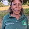 Mwanamke aliyevaa shati la polo la kijani lenye nembo za Shirika la Chakula na Kilimo la UMOJA WA MATAIFA na Huduma ya Misitu Tanzania, akiwa amesimama nje.