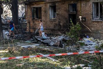 A woman and a man search for belongings amidst the rubble of a destroyed brick building in Ukraine.